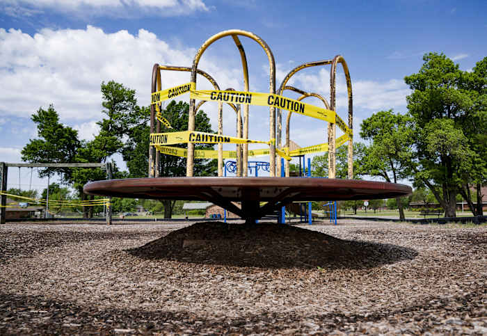 A playground spinner, roped off with caution tape.